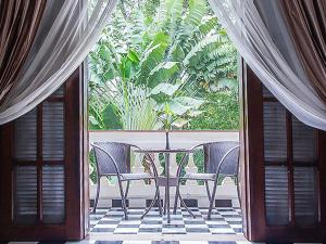 a table and chairs on a balcony with a large window at Chateau d'Angkor La Residence in Siem Reap