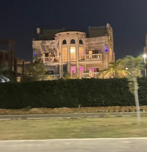un gran edificio por la noche con sus luces encendidas en Trio Villa with coverable private pool in compound near Mall of Egypt en Sheikh Zayed