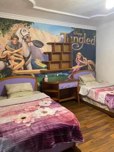 a bedroom with two beds and a disney tangled mural at Trio Villa with coverable private pool in compound near Mall of Egypt in Sheikh Zayed