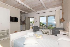 a white bedroom with a bed and a view of the ocean at Artemis Seafront Stone Studio in Petres