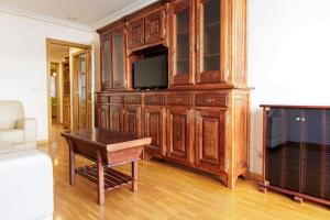 a living room with a tv and a wooden entertainment center at Apartamento Otoño - Apartamentos Nature in Cangas del Narcea