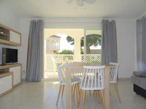 a dining room with a table and white chairs at AL101 apartamento, céntrico y piscina in Alcossebre