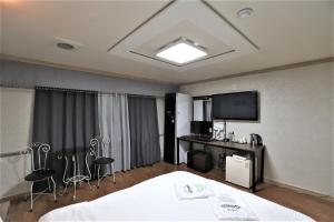 a hotel room with a bed and a desk and a television at Hani Motel in Daejeon