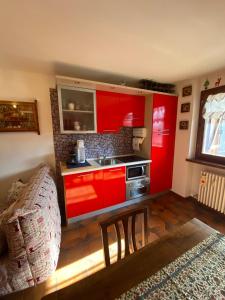 a kitchen with red cabinets and a couch in a room at Hostdomus - Grand Villard Suite in Sauze d'Oulx