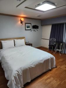 a bedroom with a large white bed and two chairs at Hani Motel in Daejeon