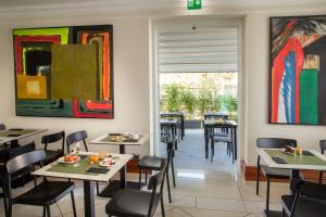 ein Restaurant mit Tischen, Stühlen und Gemälden an den Wänden in der Unterkunft Best Western Hotel Viterbo in Viterbo