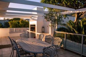 a patio with a table and chairs on a balcony at Hermanus Family Getaway - Near The Beach in Hermanus