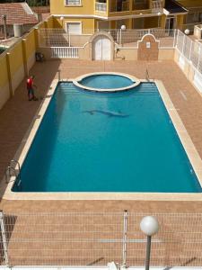 een groot blauw zwembad met een man ernaast bij Almoradi in Almoradí