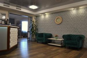 een wachtkamer met twee groene stoelen en een klok aan de muur bij Hotel Perlyna ARS in Stryi