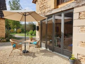 a table and chairs with an umbrella next to a building at LE SORBIER 2 BED/2 BATH GITE WITH SWIMMING POOL in Montignac