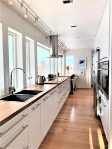 cocina grande con armarios blancos y fregadero en Villa top view Tromsø en Tromsø