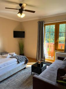 sypialnia z 2 łóżkami, telewizorem i kanapą w obiekcie Penzion Bawaria w Łomnej Górnej