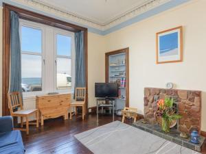 a living room with a fireplace and a television at Driftwood in North Berwick