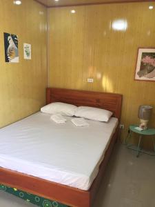 um quarto com uma cama com lençóis brancos e uma mesa em Mountaindew Garden and Pool em Roxas