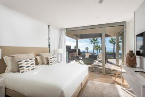 a bedroom with a large white bed and a balcony at Los Jardines de Abama Suites in Guía de Isora