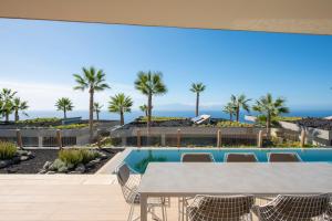a table and chairs on a patio with a view of the ocean at Los Jardines de Abama Suites in Guía de Isora