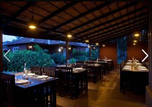 uma sala de jantar com mesas e cadeiras num restaurante em Clover Holiday Village em Madikeri