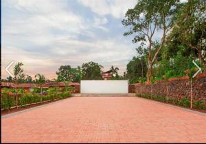 a brick driveway with a white wall and a fence at Clover Holiday Village in Madikeri