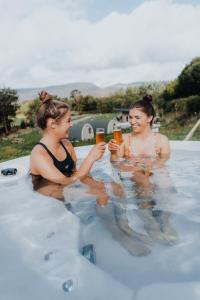 two women drinking beer in a swimming pool at Comeragh Pods in Kilmacthomas