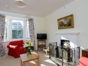 a living room with a red couch and a fireplace at Glenconner Garden Cottage in North Berwick