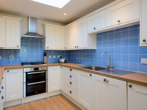 a kitchen with white cabinets and blue tiles at Glenconner Garden Cottage in North Berwick