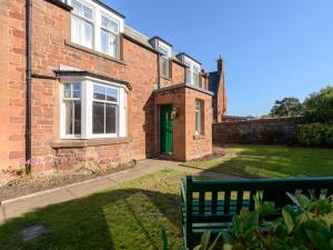 a brick house with a green door and a bench at Glenconner Garden Cottage in North Berwick
