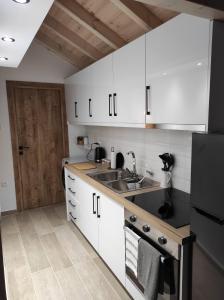 a kitchen with white cabinets and a sink at Garitsa Apartments B in Agios Rokkos