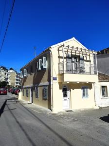 a yellow building with a balcony on a street at Garitsa Apartments B in Agios Rokkos