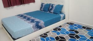 uma cama com lençóis e almofadas azuis num piso em Myra Anne Home2Stay Alor Gajah Melaka em Kampong Dalong