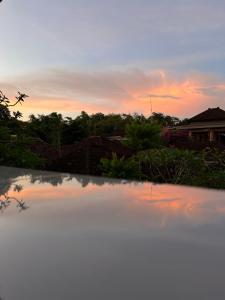 - un coucher de soleil au-dessus d'une piscine dans une cour dans l'établissement Pandu guest house, à Ubud