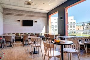 a restaurant with tables and chairs and a flat screen tv at B&B HOTEL Bois d'Arcy Saint Quentin en Yvelines in Bois-dʼArcy