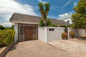 a garage with a palm tree in front of a house at Windsong Cottage in Hermanus