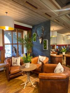 a living room with leather furniture and a table at Relais & Châteaux Jagdhof Glashütte in Bad Laasphe