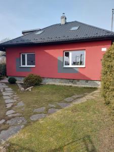 a red house with a stone path in front of it at Apartman Barbara in Lipany
