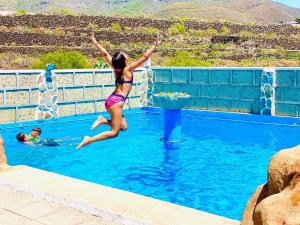 a young girl jumping into a swimming pool at Arrebol Suite con Jacuzzi piscina y naturaleza in Buzanada