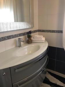 La salle de bains est pourvue d'un lavabo, d'un miroir et de serviettes. dans l'établissement Appartamento Lavanda - Casa vacanza nel Delta del Po, 