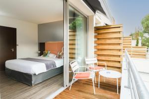 a bedroom with a bed and two chairs and a staircase at Hype Hôtel in Biscarrosse