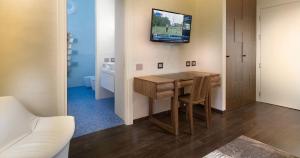 a room with a table and a television on the wall at The Glamore Milano Duomo in Milan