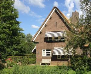 a brick house with a white awning at Hoeve Altena Apartment in Woudrichem