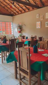 Un comedor con mesas y sillas rojas y verdes. en Pousada Arco Iris, en Gonçalves