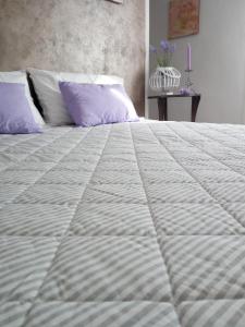 Elle comprend un grand lit blanc avec des oreillers violets. dans l'établissement Appartamento Lavanda - Casa vacanza nel Delta del Po, 
