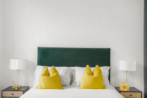 ein Bett mit zwei gelben Kissen und einem grünen Kopfteil in der Unterkunft Hububb Luxury Knightsbridge Apartments in London
