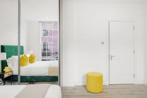 - une chambre avec un tabouret jaune devant un miroir dans l'établissement Hububb Luxury Knightsbridge Apartments, à Londres