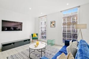 ein Wohnzimmer mit einem blauen Sofa und einem Tisch in der Unterkunft Hububb Luxury Knightsbridge Apartments in London