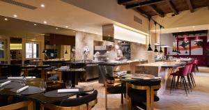 ミラノにあるThe Glamore Milano Duomoのテーブルと椅子のあるレストラン、キッチンが備わります。