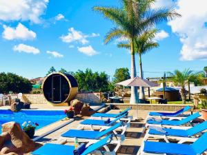 a row of blue lounge chairs next to a swimming pool at Bernegal Moneyba, Hot Tub, Piscina y Jardín in Buzanada