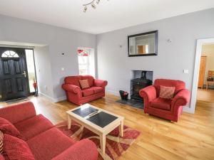 ein Wohnzimmer mit 2 roten Stühlen und einem Kamin in der Unterkunft Old Head View in Louisburgh