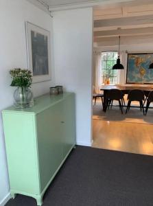 a living room with a green cabinet with a vase of flowers on it at Tinghøjgaard - Eksklusiv Gæstebolig in Fredensborg