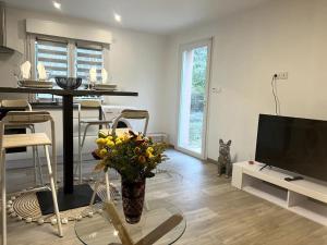 a living room with a television and a table with flowers at Entre mer et Montagne in Prades