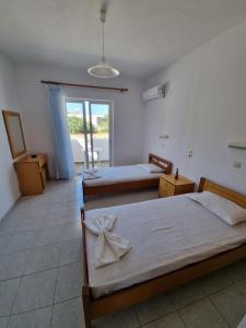 a bedroom with two beds and a balcony at White rose in Kámpos